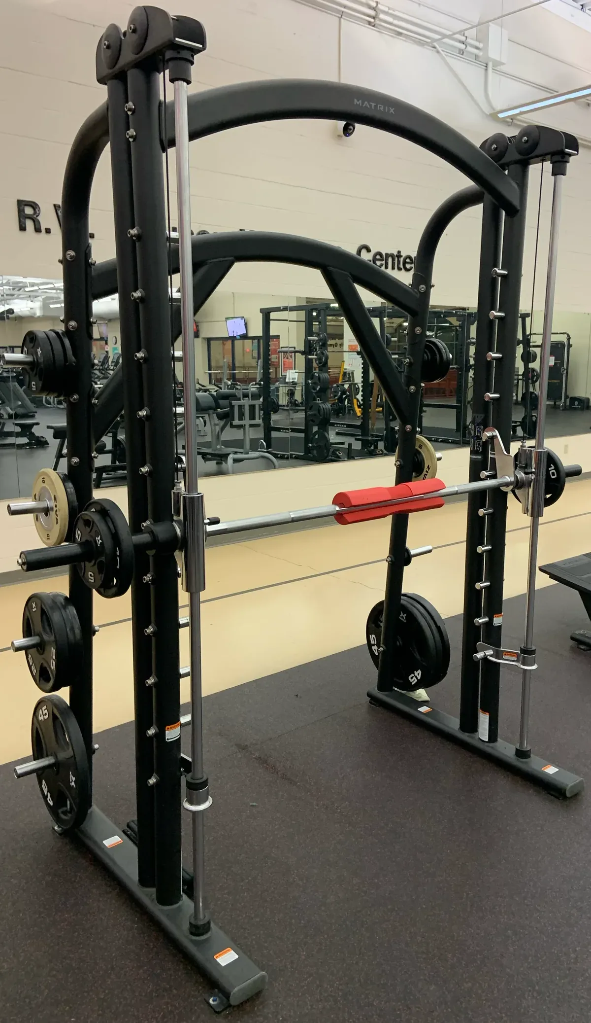 A standalone Smith machine with a guided bar, support rails and plate-storage pegs.